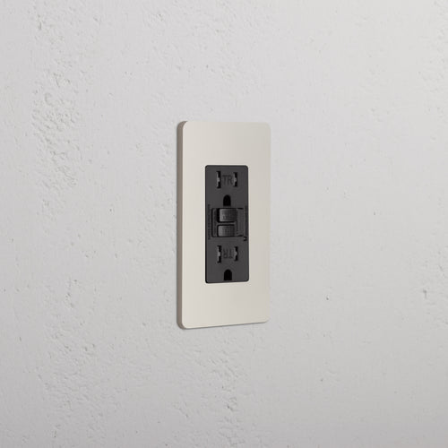Grove 1G 15A GFCI Outlet in Polished Nickel Black with white cover plate on a textured white wall.