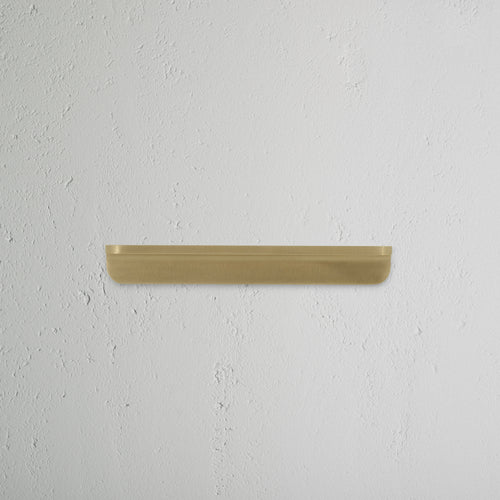Oxford Furniture Handle Small in antique brass, mounted on a textured white wall.