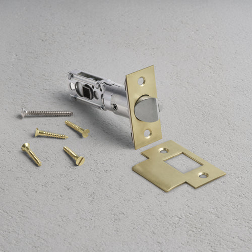 Passage Tubular Latch in Antique Brass finish, shown with matching faceplate, strike plate, and screws.