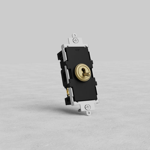 Retractive toggle switch in antique brass finish displayed on a light gray textured surface against a plain background.