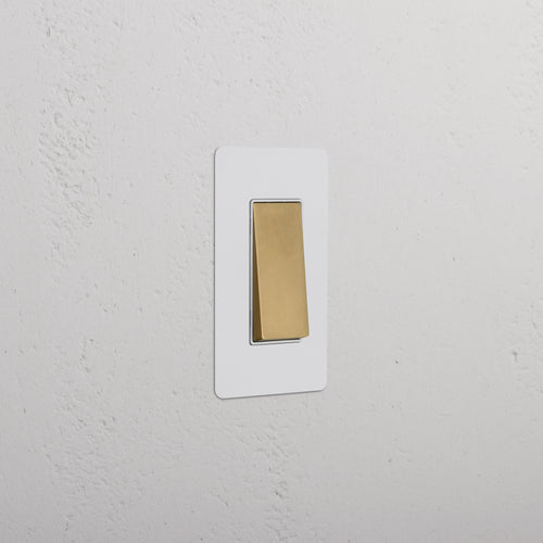 Kew 1G Rocker Switch in paintable antique brass white with gold toggle and white rectangular plate.