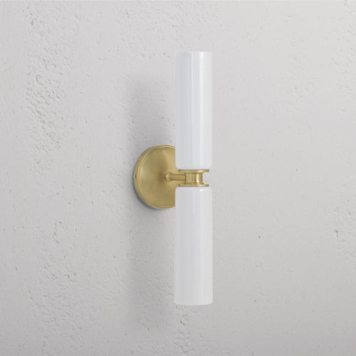 Claremont Medium Wall Light in antique brass with fine porcelain cylindrical shade, mounted on a wall.