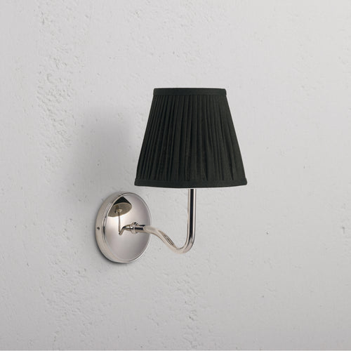 Malvern Medium Wall Light in Deep Green with polished nickel base and curved arm, mounted on a white wall.