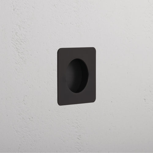 Regent Recessed Small Pull in bronze finish, square design with circular grip, mounted on white wall.