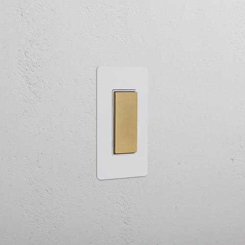 Kew 1G Center Retractive Rocker Switch in paintable antique brass white on a white background.