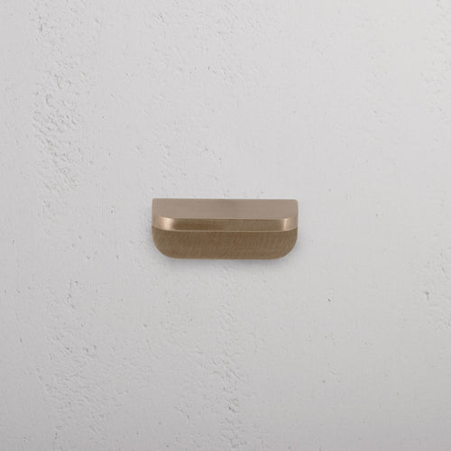 An extra small Oxford furniture handle in antique brass finish, mounted on a white surface.