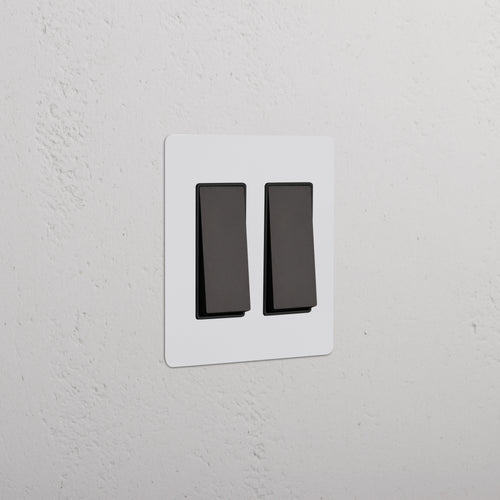 Kew 2G Rocker Switch in paintable bronze black finish, shown mounted on a white wall.