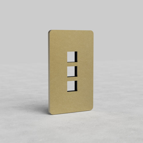 Antique brass 1-gang plate with three vertical keystone openings for Grove US, on a light gray surface.