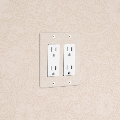 Kew 2G Outlet in clear white finish, double power socket installed on a beige wall with floral pattern.