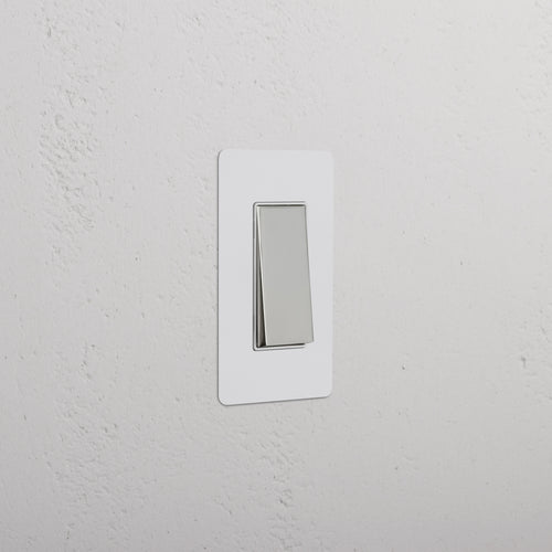 Kew 1G Rocker Switch with paintable polished nickel white plate, shown mounted on a white wall.