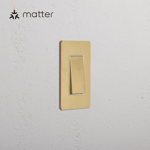 Grove 1G Smart Retractive Rocker Switch in Antique Brass White, installed on a white textured wall.