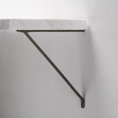 Medium bronze Brixton Shelf Bracket mounted on a light gray wall, supporting a white marble shelf.