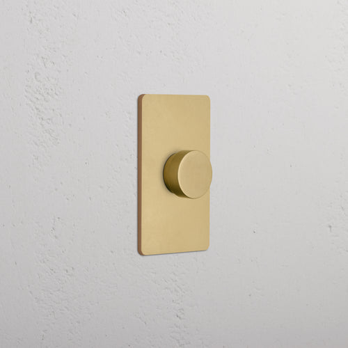 Grove 1G Dimmer Switch in Antique Brass with a round knob, shown mounted on a white wall.