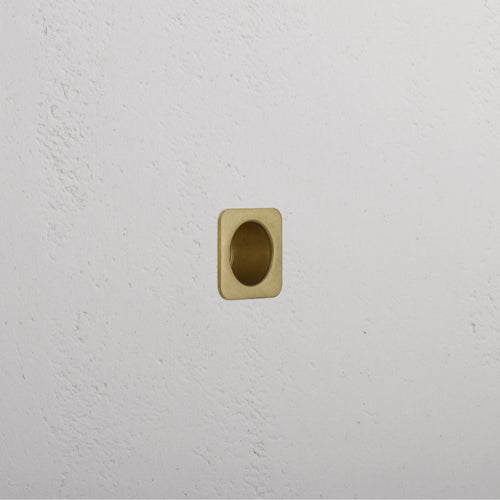 Regent Recessed Edge Pull in antique brass, square design, installed flush with a white textured wall.