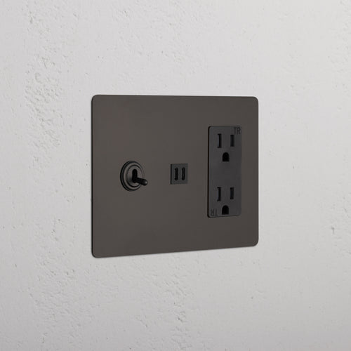 Bronze Black Kew 3G Toggle Switch, dual outlet, and fast charge USB wall plate on a white textured wall.