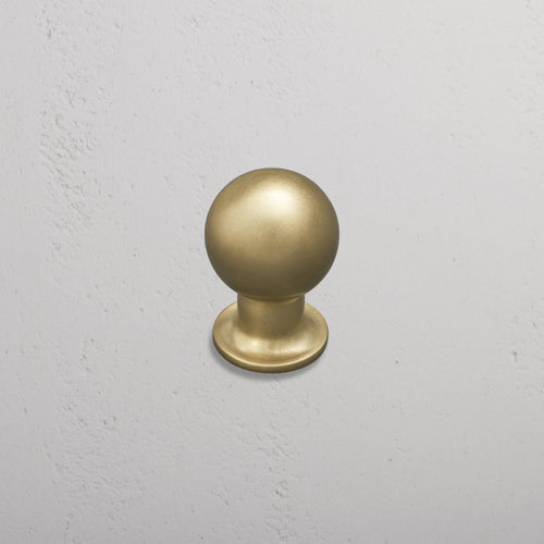 Bayswater Furniture Knob Medium in antique brass finish, installed on a light gray textured wall.