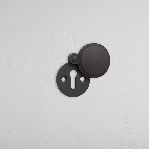 Warwick Covered Key Escutcheon in bronze finish, round design with sliding cover showing the keyhole.