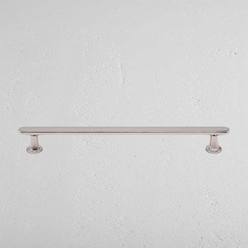 Milliner Furniture Handle Medium in polished nickel with two round bases, mounted on a white wall.