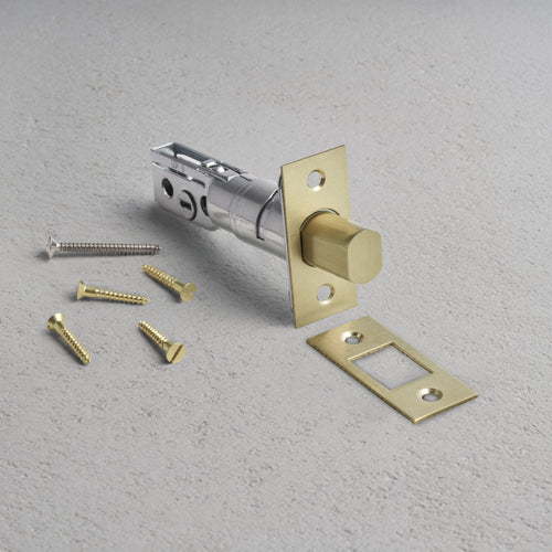 Tubular Privacy Deadbolt in Antique Brass finish with matching strike plate and screws on a light gray surface.