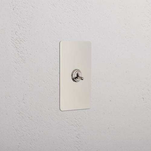 Kew 1G Toggle Switch in polished nickel with a rectangular plate and rounded corners, mounted on a wall.