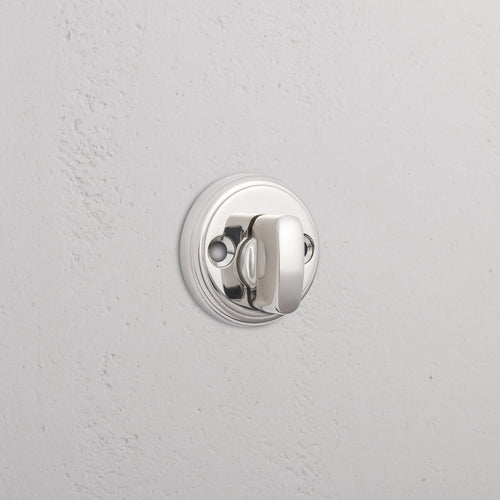 Polished nickel Canning privacy deadbolt with round design installed on a white textured door.