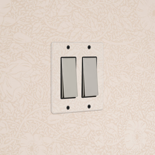 Kew 2G Rocker Switch in clear polished nickel black, double switch, mounted on beige floral wallpaper.