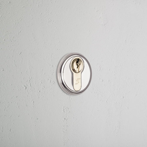 Canning Key Escutcheon in polished nickel, installed on a light gray wall, showing its circular key slot.