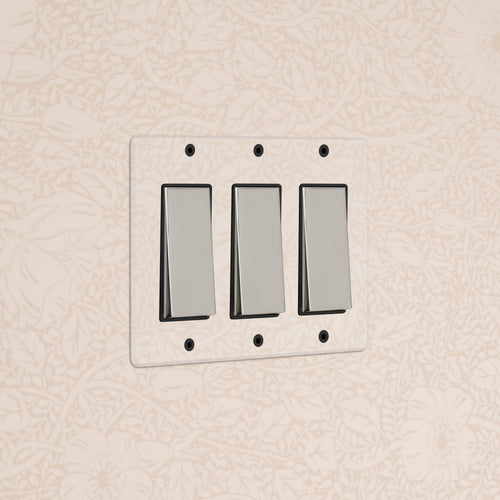 Kew 3G Rocker Switch in Clear Polished Nickel Black, shown installed on a light wall with subtle floral pattern.