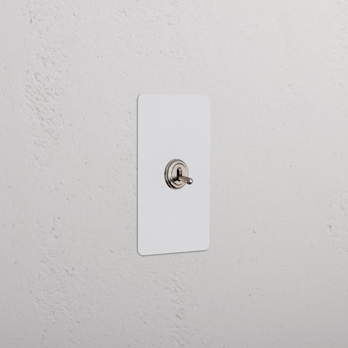 Kew 1G Four Way Toggle Switch in paintable polished nickel with a white rectangular plate on a wall.