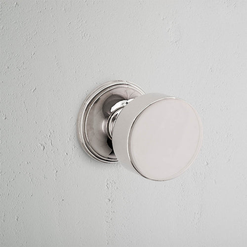 Polished nickel Onslow Passage Door Knob Set with round design, installed on a light gray door.