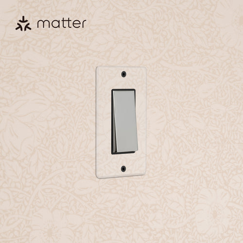 Kew 1G Smart Retractive Rocker Switch in clear polished nickel black, mounted on floral wallpapered wall.