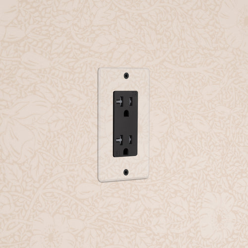Kew 1G 20A Outlet in Clear Black with a transparent cover plate installed on a beige floral-patterned wall.