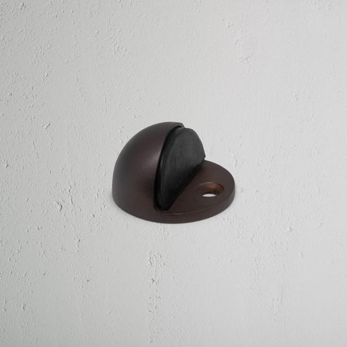 Clifton Half Moon Door Stop in bronze finish with rubber bumper, mounted on a light wall.