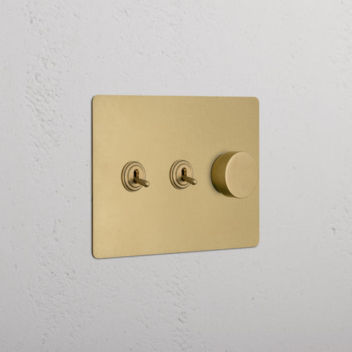 Kew 3G 2x Toggle & Dimmer Switch in antique brass with two toggle switches and one dimmer knob.